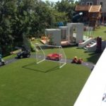 artificial turf backyard with soccer goal at one end and black track surrounding