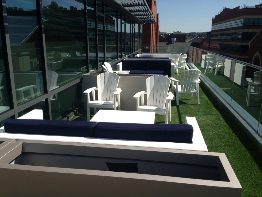 hotel rooftop lounge area with artificial turf white and navy blue furniture