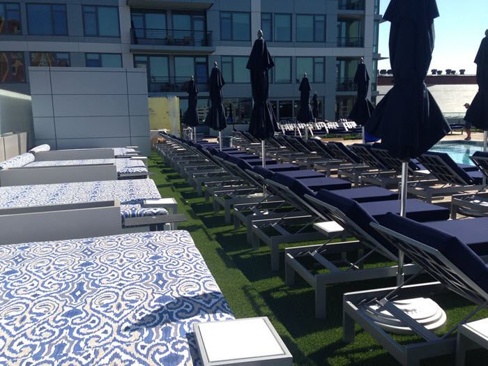 health club rooftop with artificial turf pool and navy blue pool side lounge chairs and umbrellas