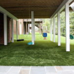 under deck artificial turf with children's swings hanging from deck